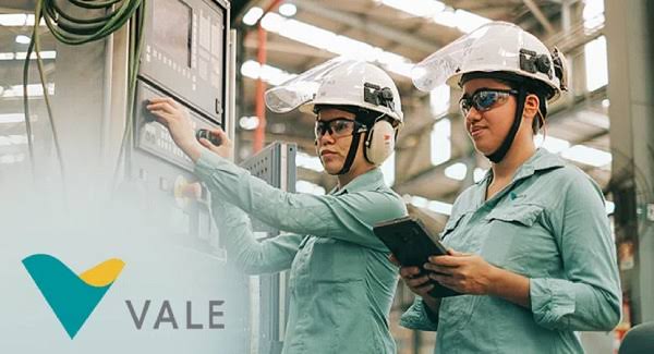 Photo with a view from above of a Vale employee in the middle of a plantation. The employee is looking up and is wearing a helmet, goggles, Vale uniform and green vest
